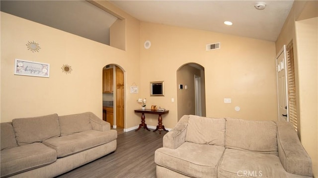 living room featuring visible vents, arched walkways, wood finished floors, and vaulted ceiling