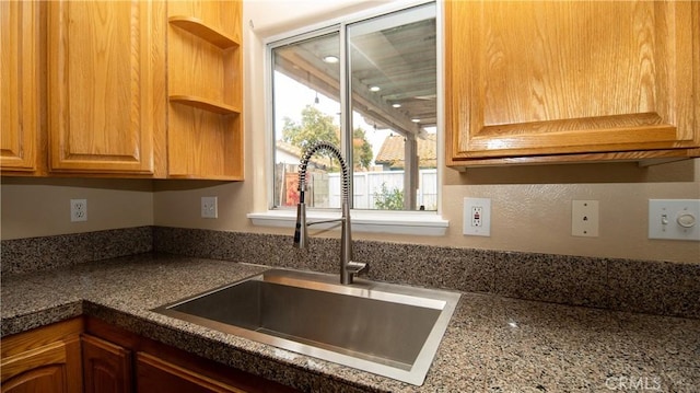 kitchen featuring dark countertops, open shelves, and a sink