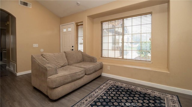 living area featuring visible vents, baseboards, lofted ceiling, dark wood-style floors, and arched walkways