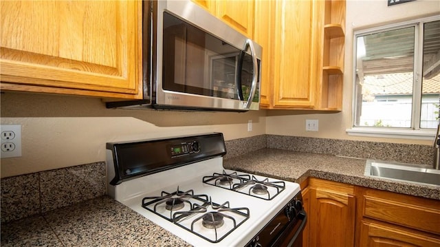 kitchen with tile countertops, open shelves, a sink, stainless steel microwave, and white gas range