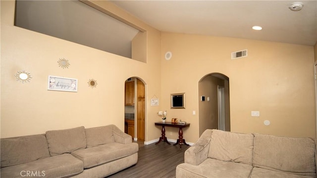 living area with visible vents, baseboards, vaulted ceiling, wood finished floors, and arched walkways