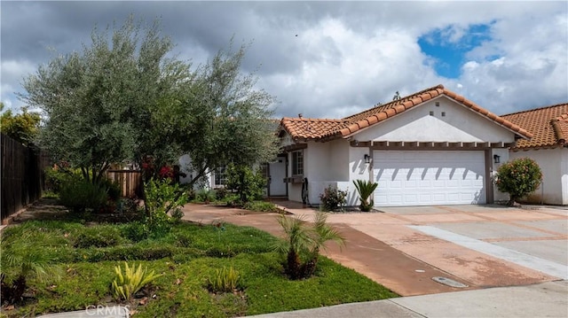 mediterranean / spanish-style house with fence, a tile roof, concrete driveway, stucco siding, and a garage