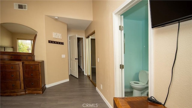 hall featuring visible vents, baseboards, and dark wood-style flooring