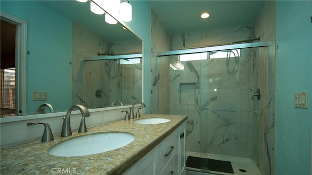 full bath with a marble finish shower, double vanity, and a sink