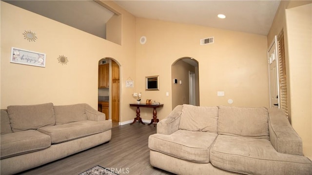 living area featuring visible vents, wood finished floors, recessed lighting, arched walkways, and baseboards