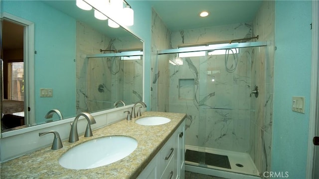 full bathroom with a sink, a marble finish shower, and double vanity