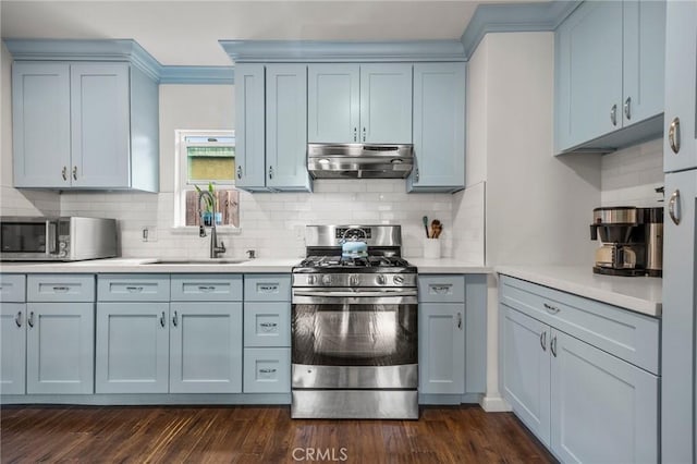 kitchen featuring dark wood-type flooring, under cabinet range hood, light countertops, appliances with stainless steel finishes, and a sink