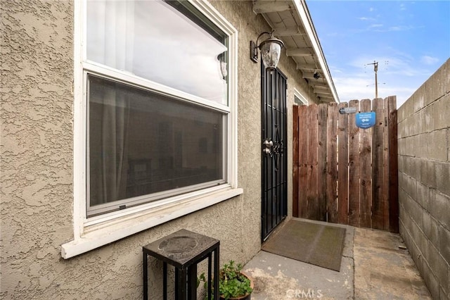 view of exterior entry featuring fence and stucco siding