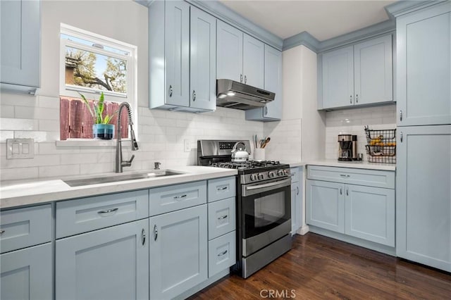 kitchen featuring dark wood-type flooring, under cabinet range hood, light countertops, gas stove, and a sink