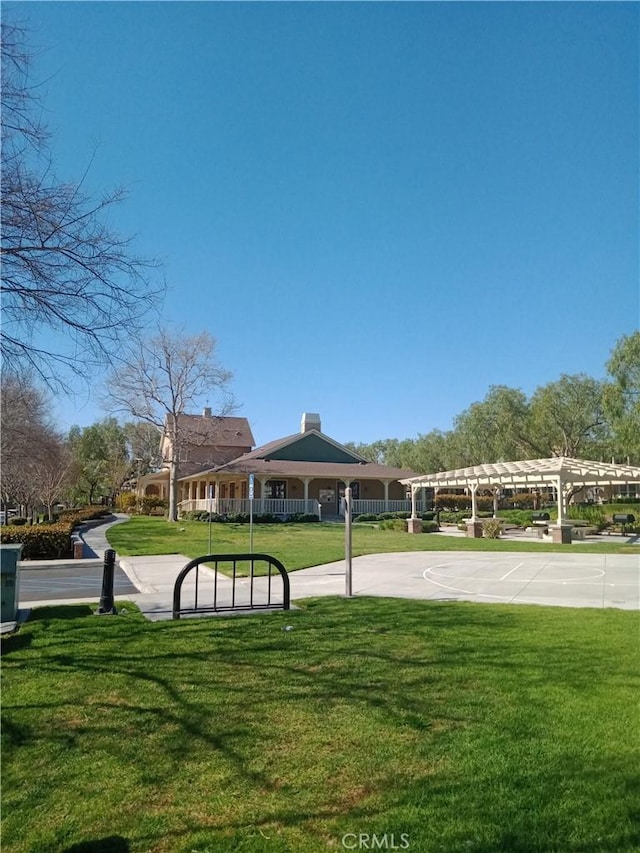 surrounding community featuring community basketball court, a yard, and a pergola