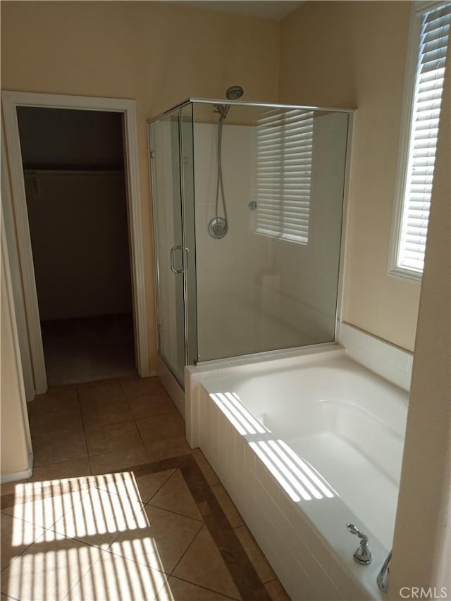 full bathroom with tile patterned floors, a spacious closet, a garden tub, and a stall shower