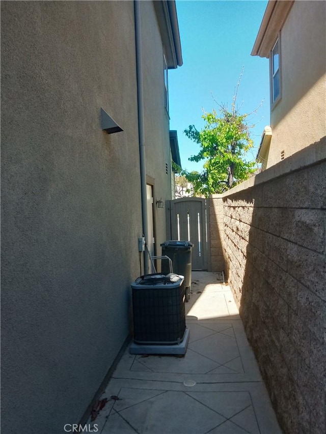 view of home's exterior with a patio area, stucco siding, central AC, and fence