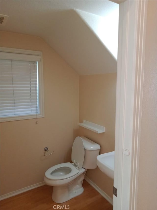 bathroom featuring visible vents, baseboards, toilet, vaulted ceiling, and wood finished floors