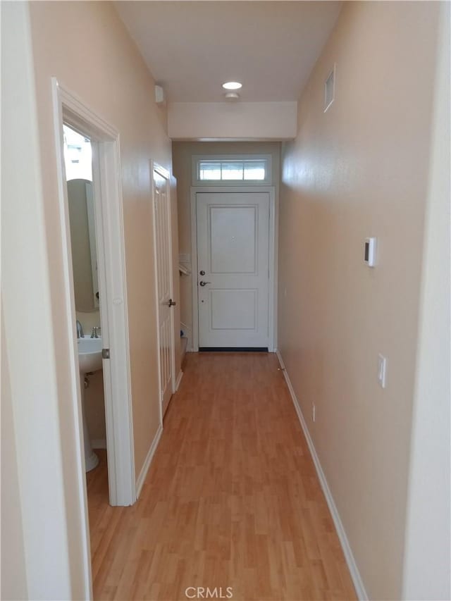 doorway with light wood-type flooring, baseboards, and visible vents