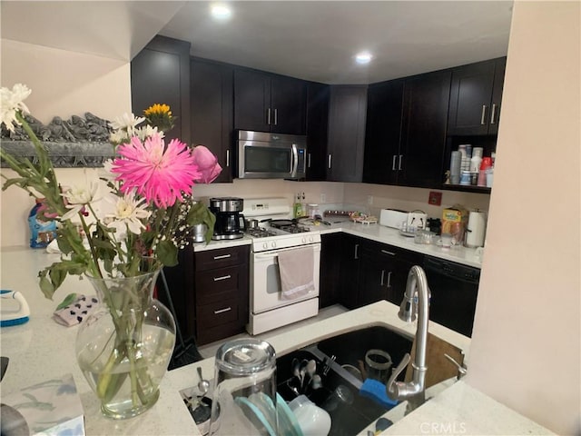 kitchen featuring dark cabinets, stainless steel microwave, dishwasher, and white range with gas cooktop