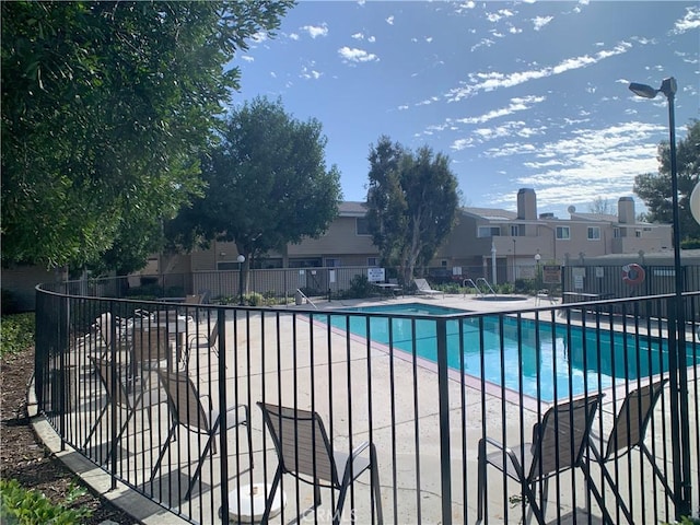 community pool with a patio area and fence