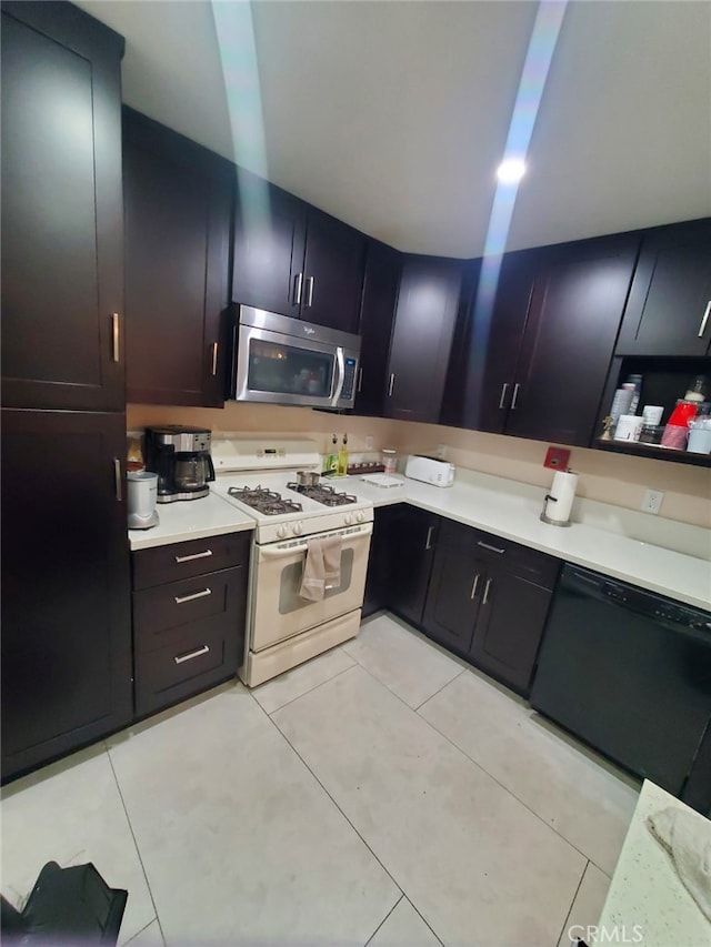 kitchen featuring white range with gas stovetop, light tile patterned flooring, light countertops, dishwasher, and stainless steel microwave