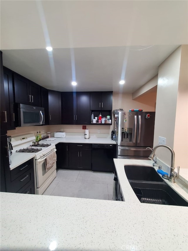 kitchen featuring a sink, dark cabinetry, recessed lighting, stainless steel appliances, and light tile patterned floors