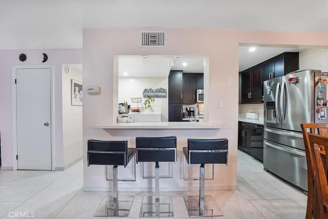 9920 Sepulveda Blvd Unit 1, Mission Hills San Fernando, CA 91345 - kitchen featuring appliances with stainless steel finishes, a breakfast bar, light countertops, light tile patterned flooring, and a sink