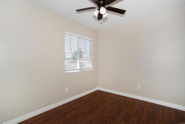 spare room featuring baseboards, dark wood-style floors, and a ceiling fan