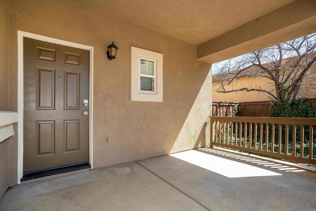 entrance to property with stucco siding and fence