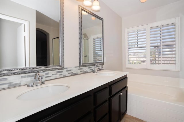 full bath featuring a garden tub, double vanity, tasteful backsplash, and a sink