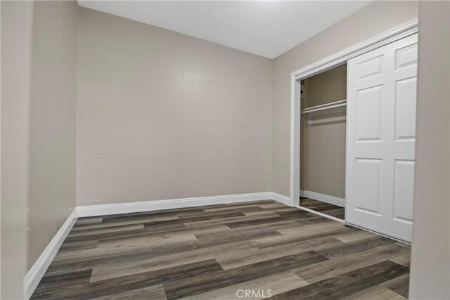 unfurnished bedroom featuring a closet, baseboards, and wood finished floors