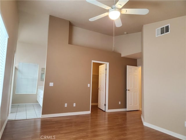 unfurnished bedroom featuring visible vents, baseboards, a walk in closet, and wood finished floors