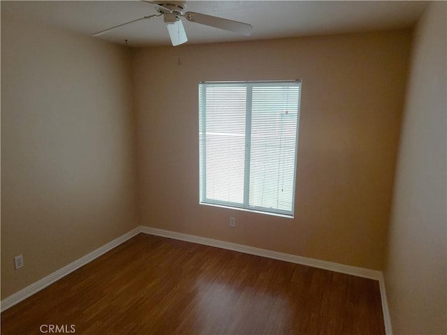 empty room featuring ceiling fan, baseboards, and wood finished floors