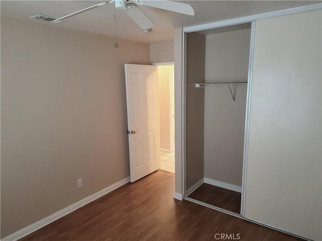 unfurnished bedroom with visible vents, wood finished floors, a closet, and baseboards