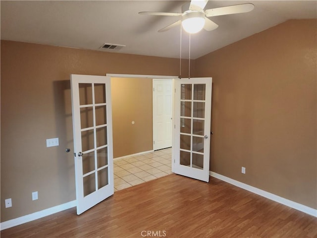 spare room featuring visible vents, wood finished floors, ceiling fan, and french doors