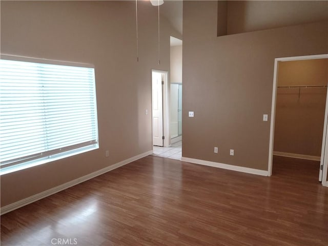 spare room with a high ceiling, baseboards, and wood finished floors