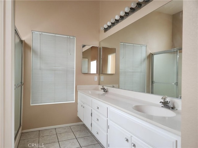 bathroom with tile patterned floors, a shower with shower door, double vanity, and a sink