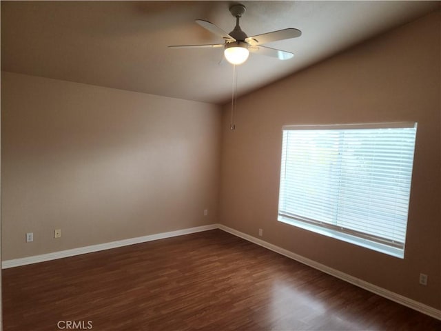 unfurnished room with vaulted ceiling, a ceiling fan, dark wood-style flooring, and baseboards