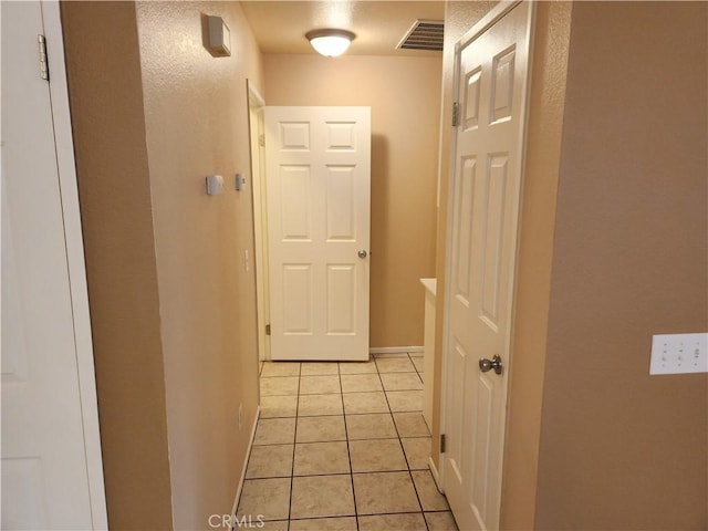 hall featuring light tile patterned floors and visible vents