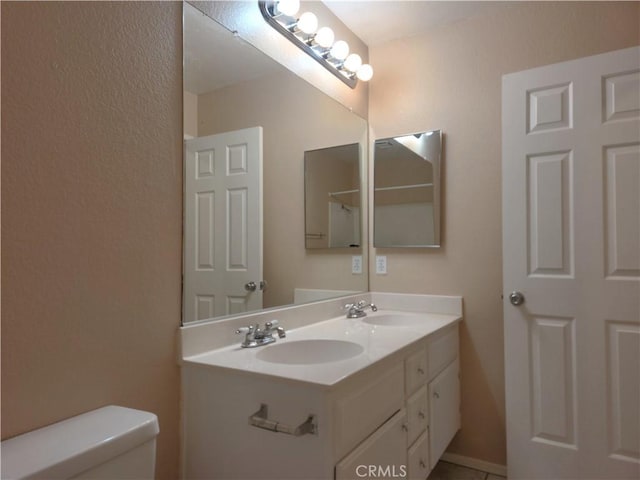 full bathroom with double vanity, toilet, and a sink