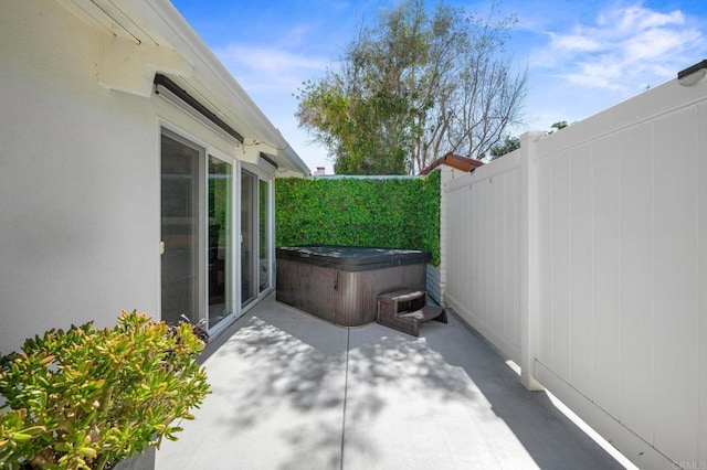 view of patio / terrace featuring fence and a hot tub