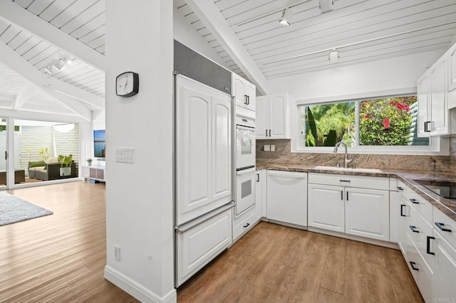 kitchen with backsplash, white appliances, white cabinetry, and a sink