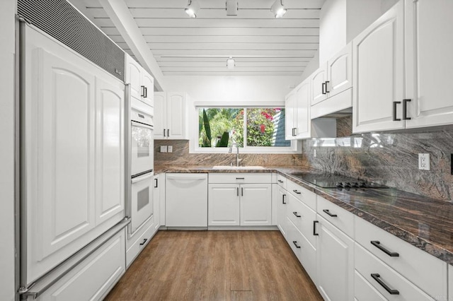 kitchen featuring tasteful backsplash, dark wood-style floors, white appliances, white cabinetry, and a sink