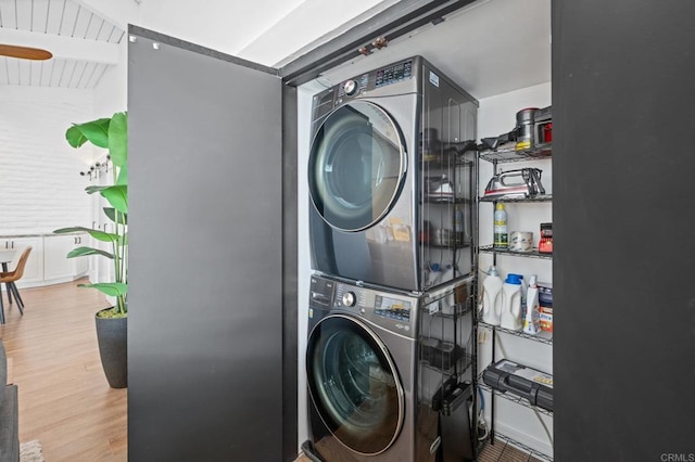 laundry area with laundry area, stacked washer / dryer, and wood finished floors