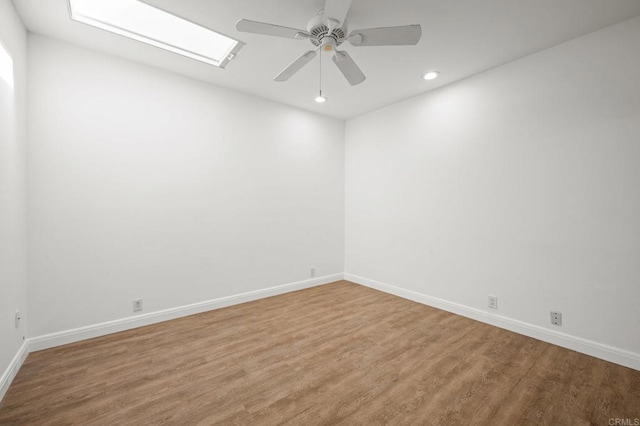 unfurnished room featuring recessed lighting, a skylight, baseboards, and wood finished floors