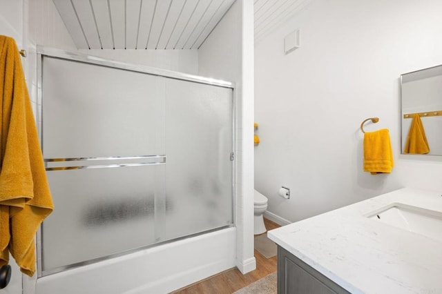 full bathroom with vanity, toilet, wood finished floors, and enclosed tub / shower combo