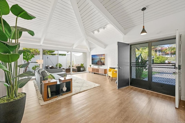 living room featuring beamed ceiling, track lighting, a sunroom, and wood finished floors