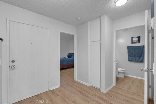 interior space with baseboards, toilet, wood finished floors, and a textured ceiling