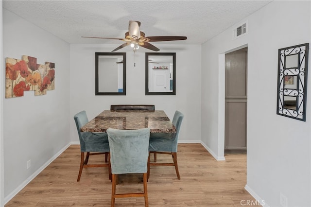 dining space with visible vents, light wood-style floors, ceiling fan, and a textured ceiling