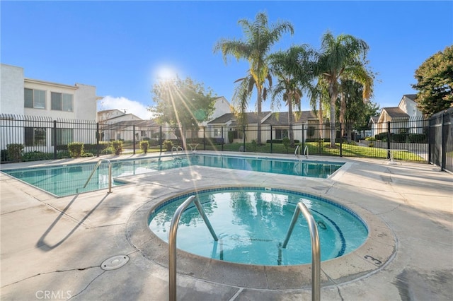 pool featuring a patio area, a residential view, fence, and a hot tub