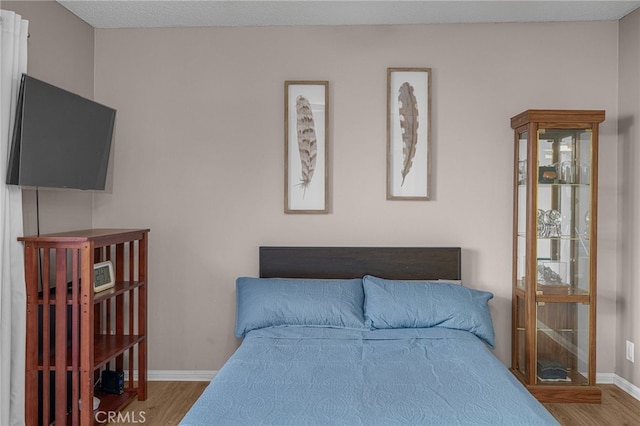 bedroom with baseboards and wood finished floors