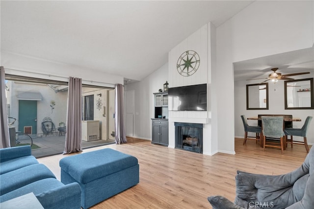 living area featuring baseboards, light wood-style flooring, a fireplace, high vaulted ceiling, and a ceiling fan