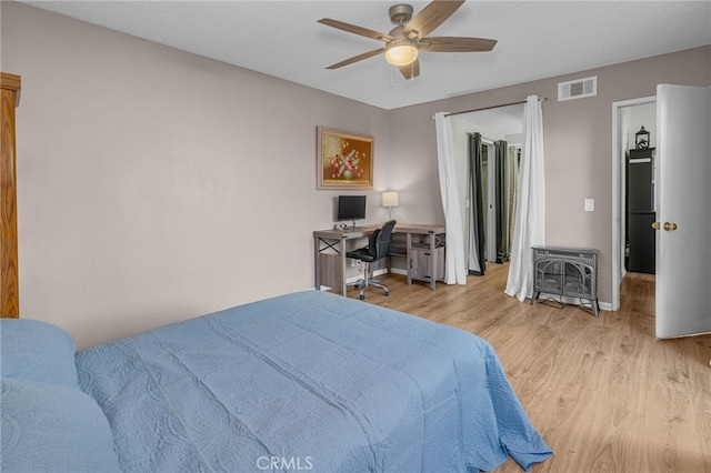 bedroom with visible vents, baseboards, wood finished floors, and a ceiling fan