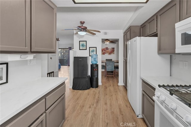 kitchen with a ceiling fan, a textured ceiling, white appliances, light wood finished floors, and light countertops